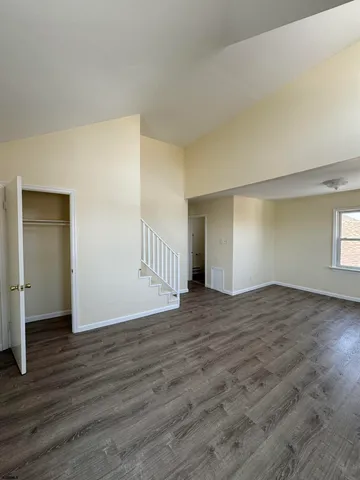 a view of an empty room with window and wooden floor