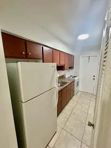 a kitchen with a refrigerator a stove top oven and cabinets