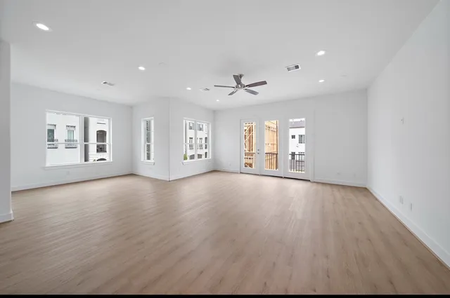 a view of an empty room with a window and wooden floor