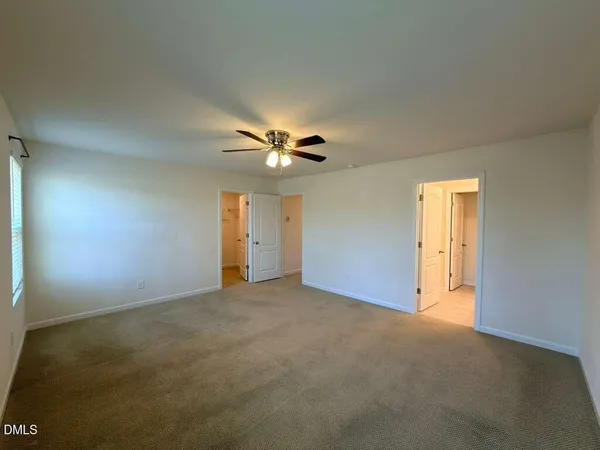 a view of an empty room with a ceiling fan and window