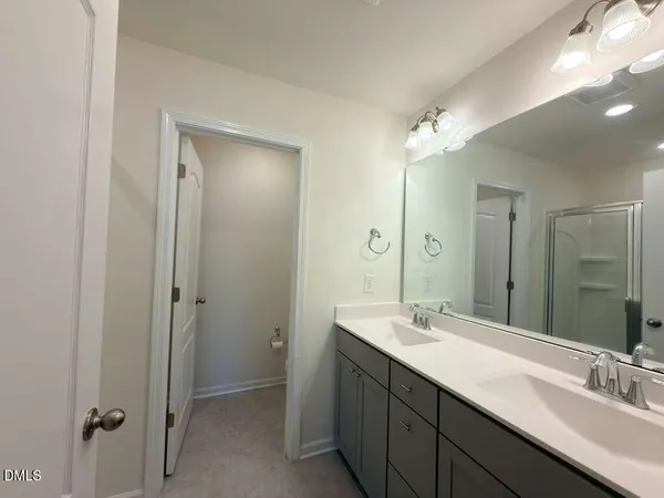 a bathroom with a double vanity sink mirror and shower