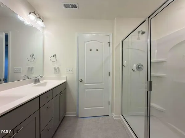 a bathroom with a double vanity sink mirror and shower