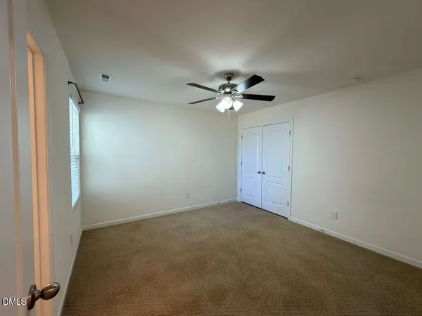 a view of an empty room with a chandelier fan