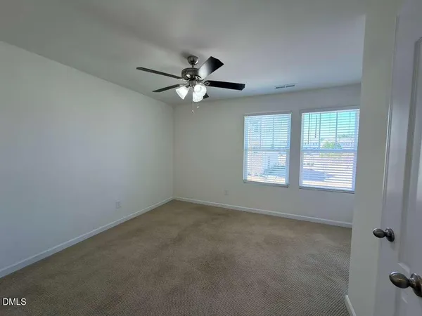 an empty room with a window and a fan