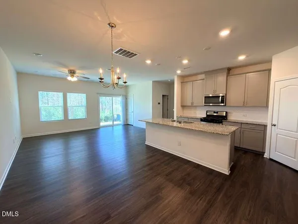 a kitchen with stainless steel appliances granite countertop a refrigerator a sink dishwasher a stove and white countertops with wooden floor