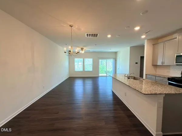 a large kitchen with granite countertop a large counter top a sink stainless steel appliances and cabinets