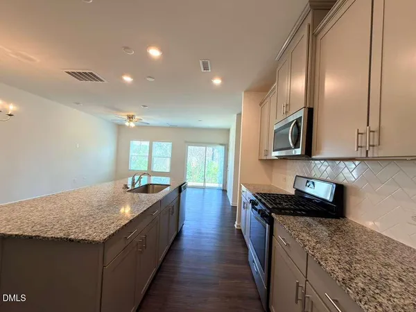 a kitchen with granite countertop sink stove and cabinets