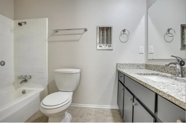 a bathroom with a granite countertop toilet a sink and a bathtub