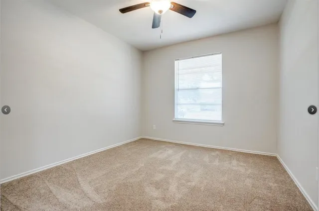 an empty room with a window and a ceiling fan