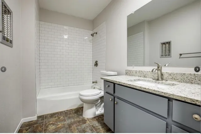 a bathroom with a granite countertop sink a toilet a mirror a bathtub and shower