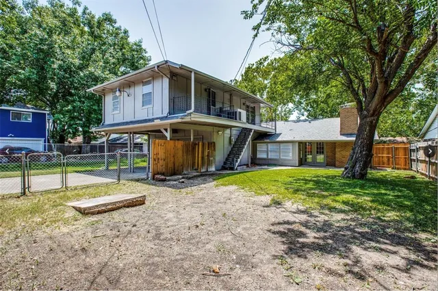 a view of a house with a yard and a large tree