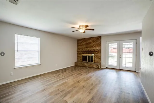 an empty room with wooden floor and chandelier fan