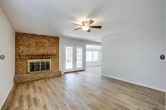 wooden floor fireplace and windows in an empty room