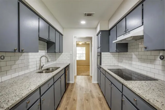 a kitchen with granite countertop stainless steel appliances a sink stove top oven and cabinets
