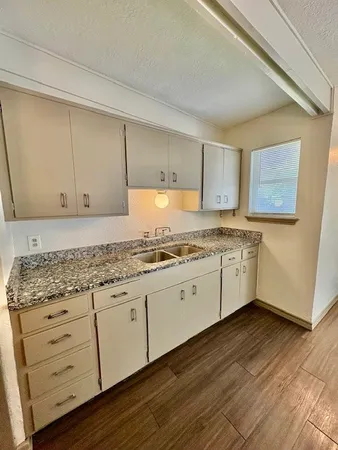 a kitchen with granite countertop a sink cabinets and wooden floor