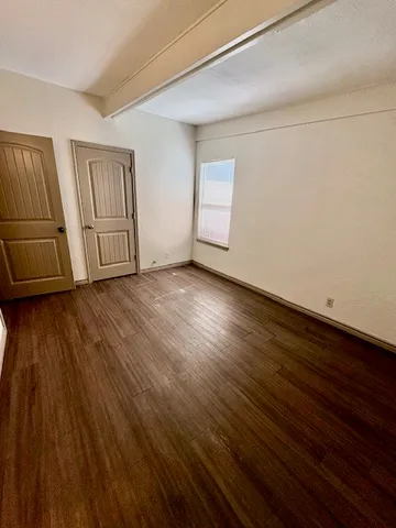 a view of an empty room with window and wooden floor