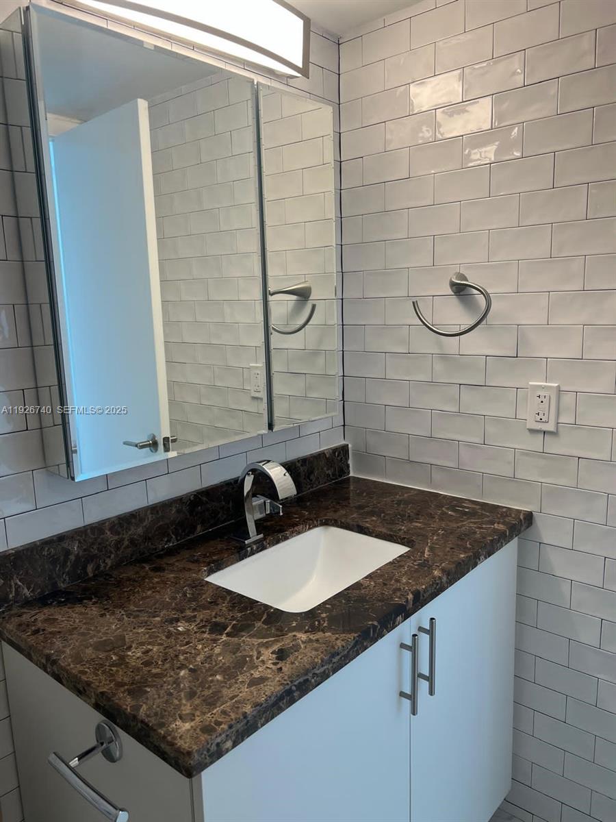 9273 Collins Avenue, Unit 606 Surfside, FL 33154 - Photo 17 of 18 a bathroom with a granite countertop sink and a mirror