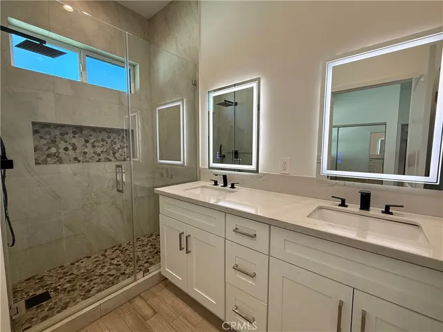 a bathroom with a double vanity sink mirror and shower