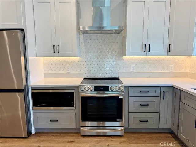 a kitchen with granite countertop a stove and a refrigerator with white cabinets