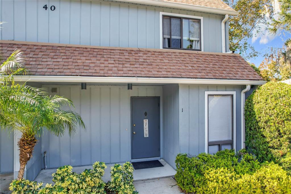 a view of a house with a small yard plants and large tree