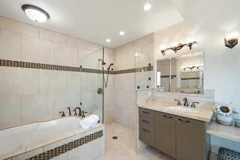 a spacious bathroom with a tub sink and mirror
