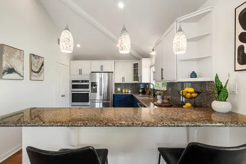 a kitchen with granite countertop counter space a sink and chairs