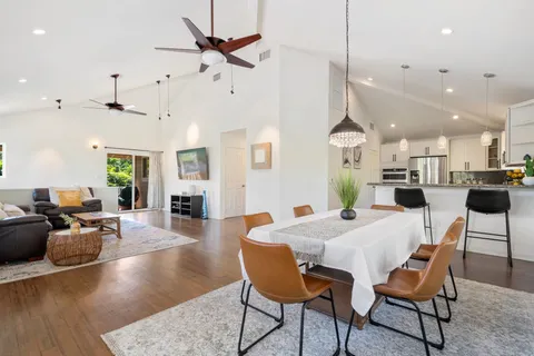 a view of a dining room and livingroom with furniture wooden floor a chandelier