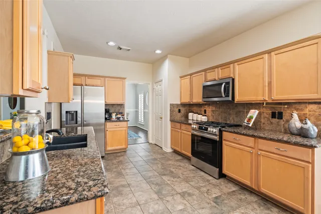 a kitchen with stainless steel appliances granite countertop a stove top oven a sink a dining table and chairs