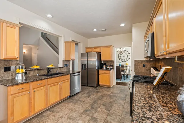 a kitchen with stainless steel appliances granite countertop a stove a sink and a microwave