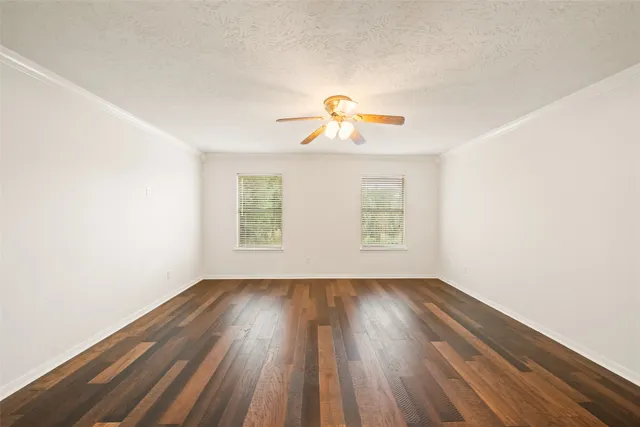 a view of a room with wooden floors and ceiling fan