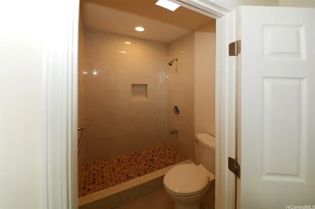 a bathroom with a granite countertop toilet a sink a shower and a window