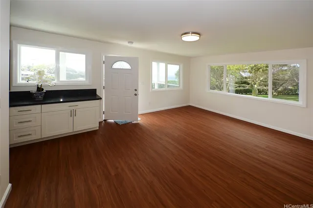 an empty room with wooden floor and windows