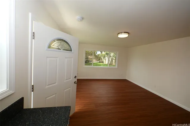 an empty room with wooden floor closet and windows