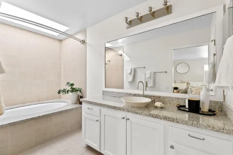 a bathroom with a granite countertop sink mirror and bathtub