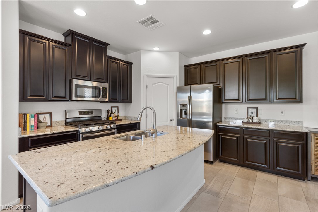 891 Earth Luster Road Las Vegas, NV 89178 - Photo 6 of 48 Granite counters and dark cabinetry create a sleek, contemporary kitchen space.