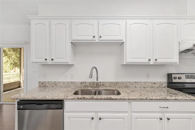 a kitchen with stainless steel appliances granite countertop white cabinets and a stove