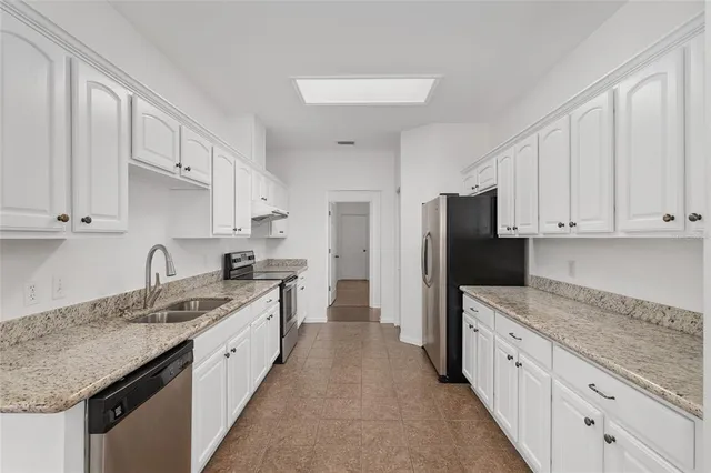 a kitchen with granite countertop white cabinets and a sink