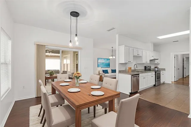 a open dining room with stainless steel appliances kitchen island granite countertop a dining table chairs and a refrigerator