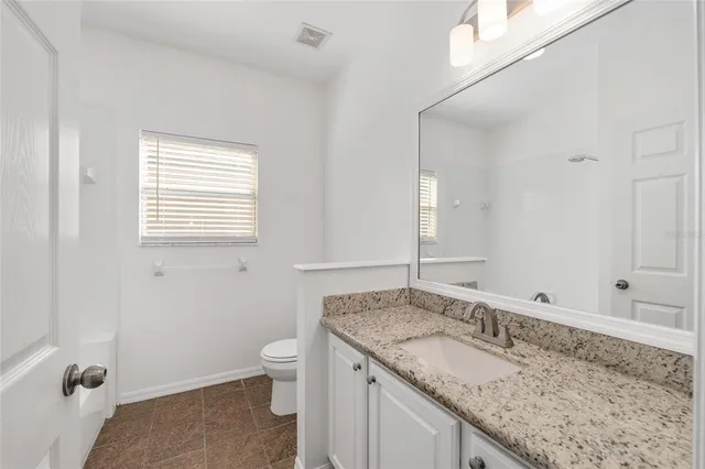 an empty room with wooden floor ceiling fan and windows
