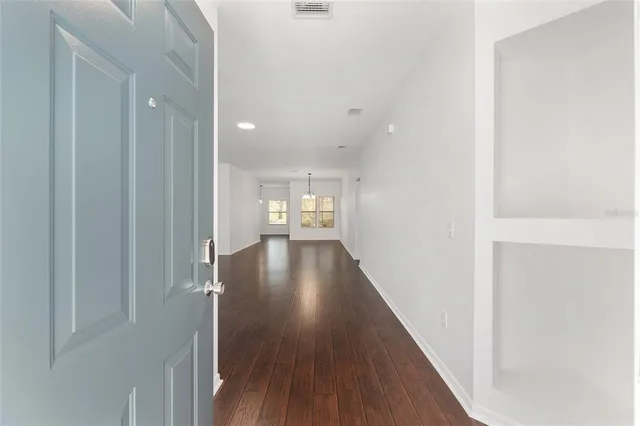 an empty room with wooden floor cabinet and windows