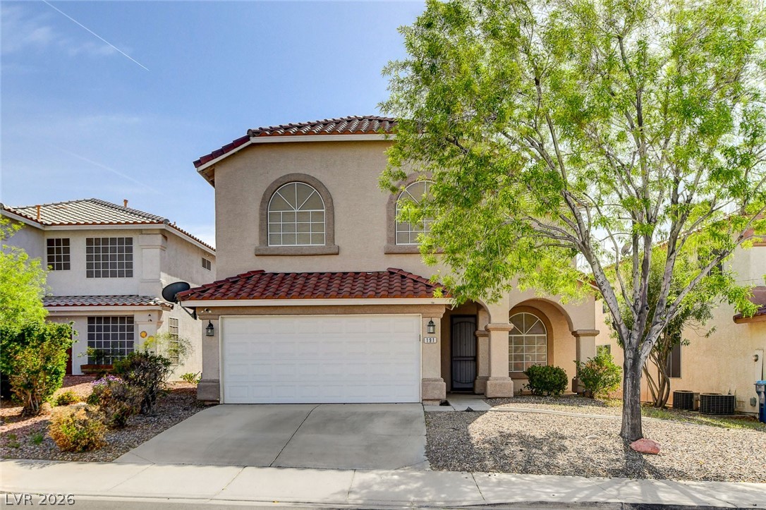 Mediterranean / spanish-style home featuring stucco siding, driveway, a tile roof, an attached garage, and central AC unit