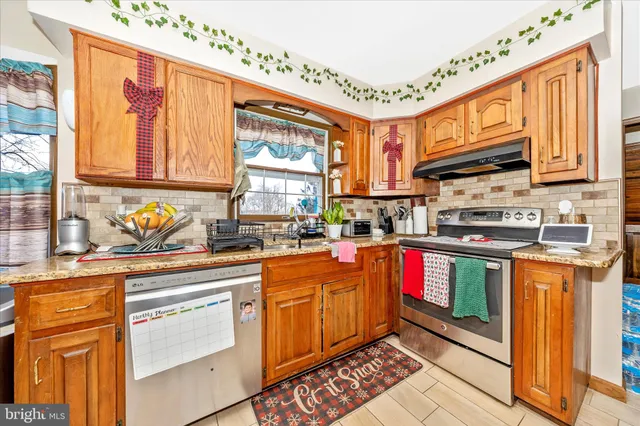 a view of kitchen with stainless steel appliances granite countertop a refrigerator and a stove top oven