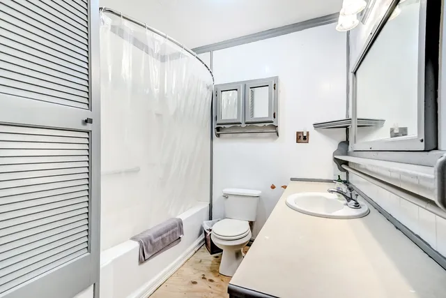 a bathroom with a granite countertop sink toilet a mirror and shower