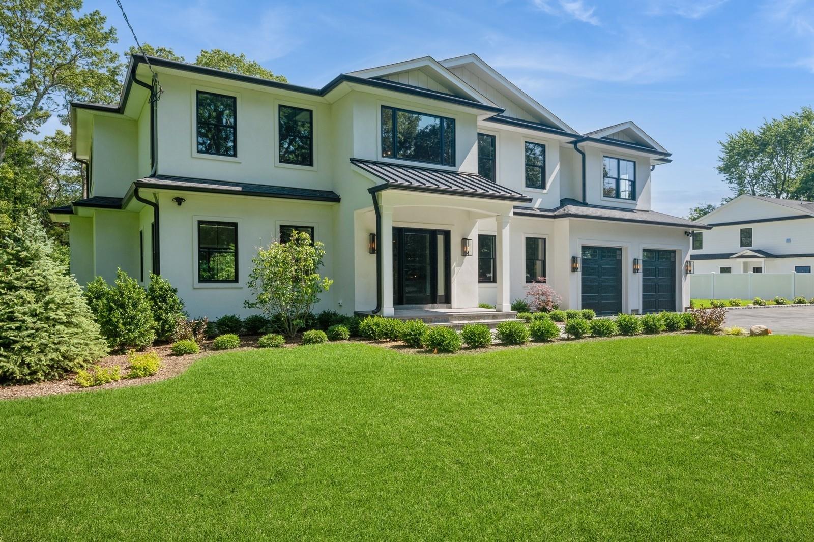 Modern farmhouse style home featuring driveway, an attached garage, a standing seam roof, stucco siding, and a metal roof