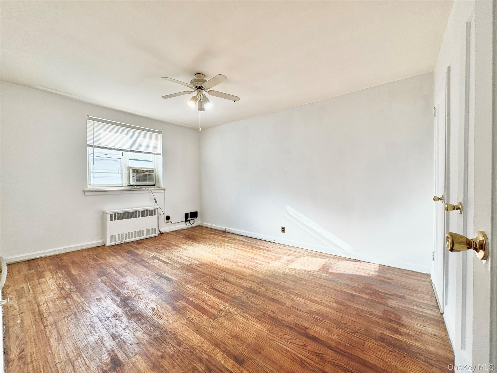 35-40 Clearview Expressway, Unit 371 Queens, NY 11361 - Photo 5 of 10 an empty room with wooden floor ceiling fan and windows