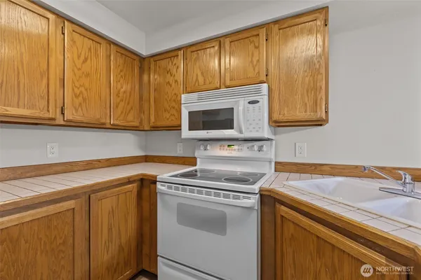 a view of kitchen with a sink a microwave and cabinets