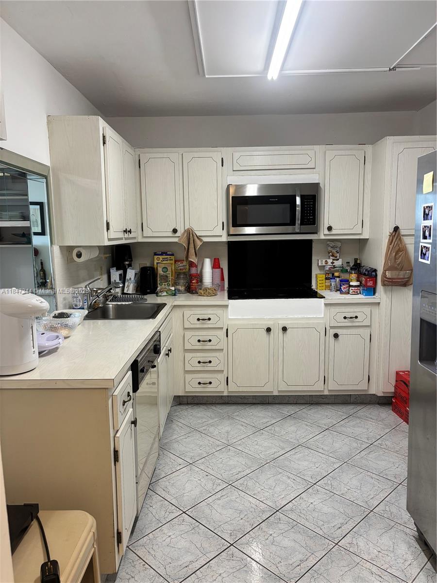 427 Golden Isles Drive, Unit 12B Hallandale Beach, FL 33009 - Photo 2 of 10 a kitchen with stainless steel appliances a sink a stove a microwave a sink a refrigerator and cabinets
