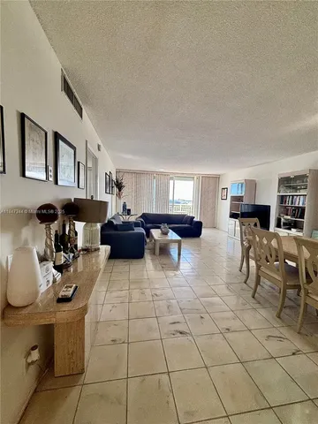 a living room with furniture and a dining table with kitchen appliances