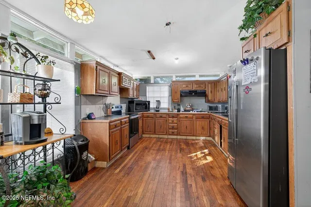 a kitchen with stainless steel appliances granite countertop a refrigerator a stove and a wooden floors