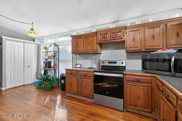 a kitchen with granite countertop wood cabinets stainless steel appliances and a counter space